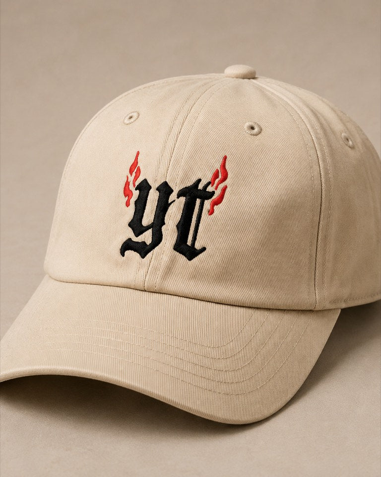 Cream YapThreads dad cap embroidered with the blackletter yt monogram and red flames